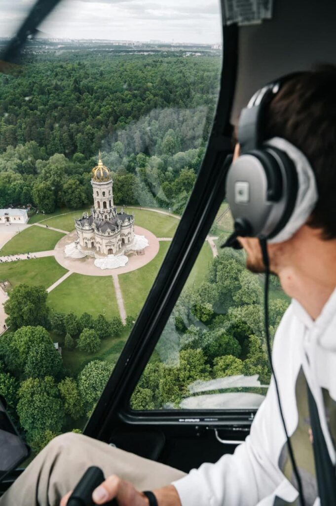Пилот вертолета на фоне Храма в Дубровицах при полете от компании "Captour"