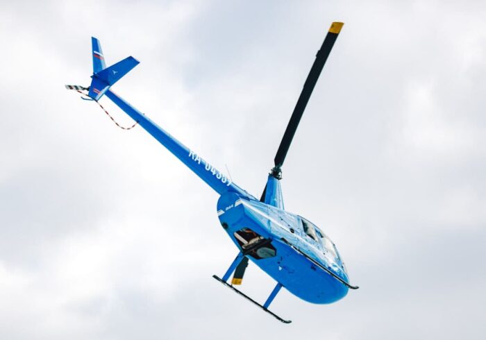 Синий вертолёт Robinson R44 в небе в полете от компании "Captour"