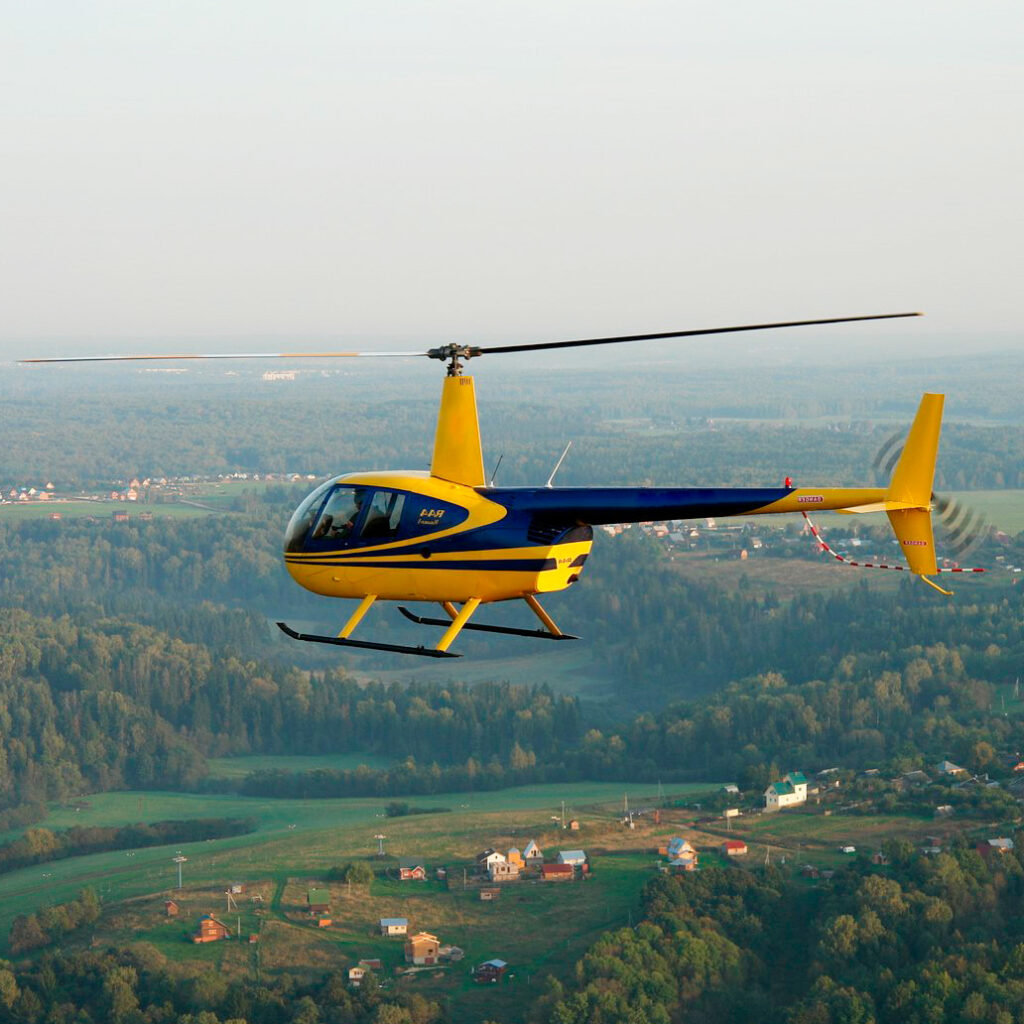 Вертолет Robinson R44 в небе в полёте от компании "Captour"