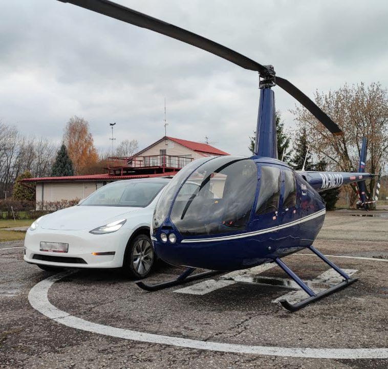 Белая Tesla Y и синий вертолёт от компании "Captour"