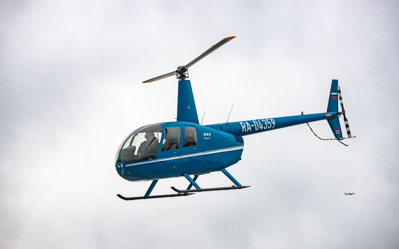 Синий вертолёт Robinson R44 в небе от компании "Captour"