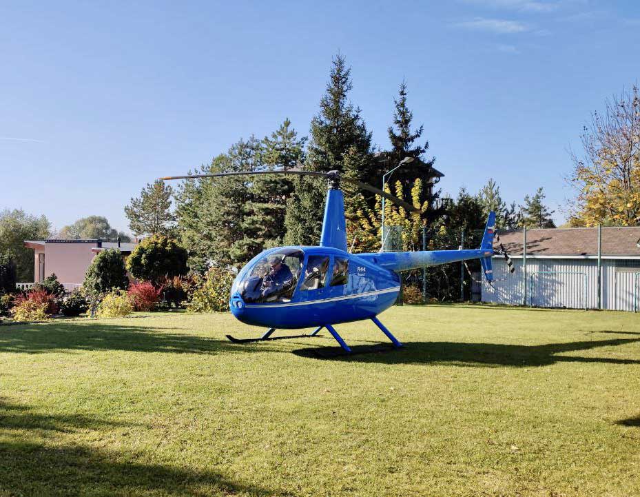 Вертолет Robinson R44 стоит на лужайке и готовится к взлету